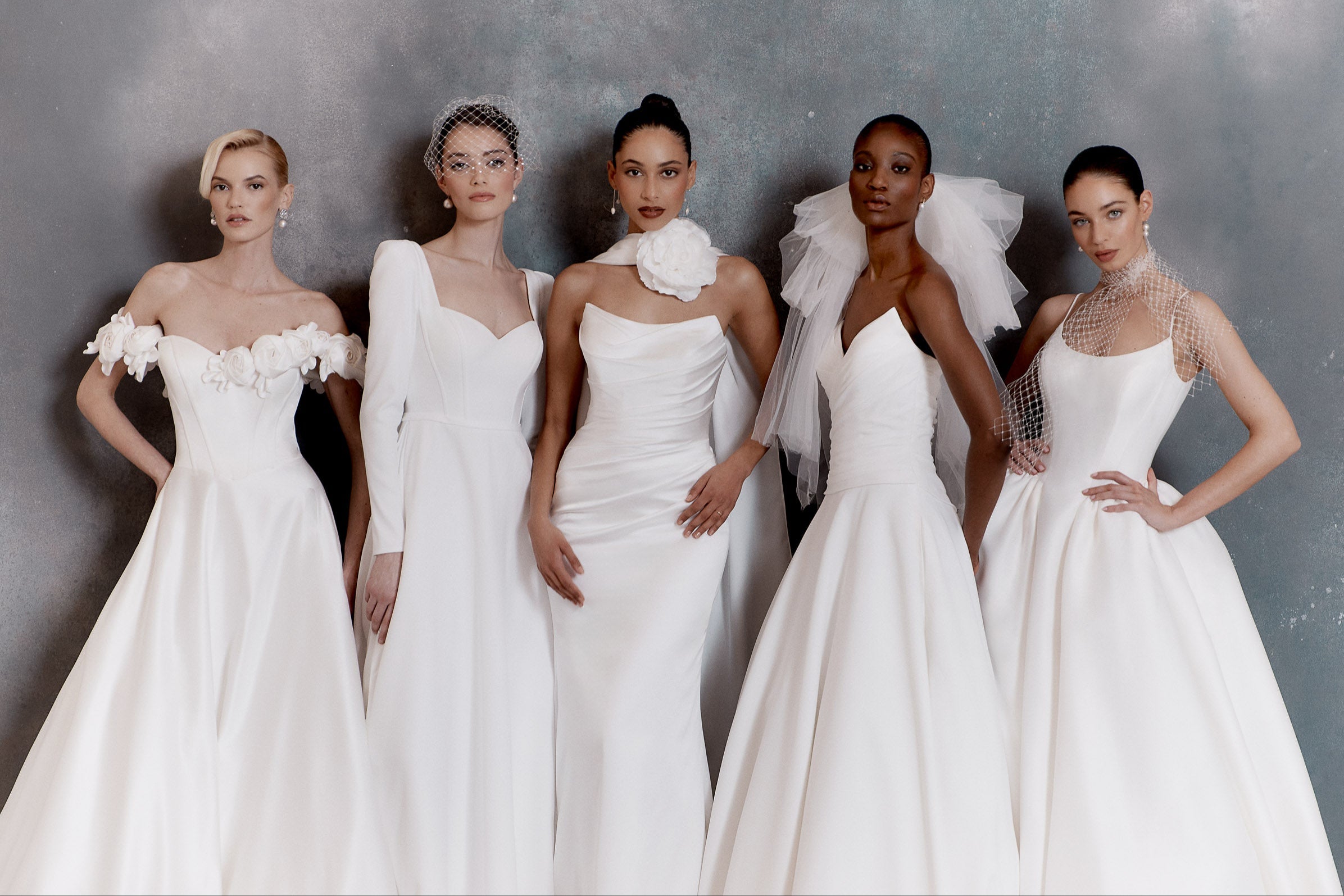 Five women in white wedding dresses against a gray background